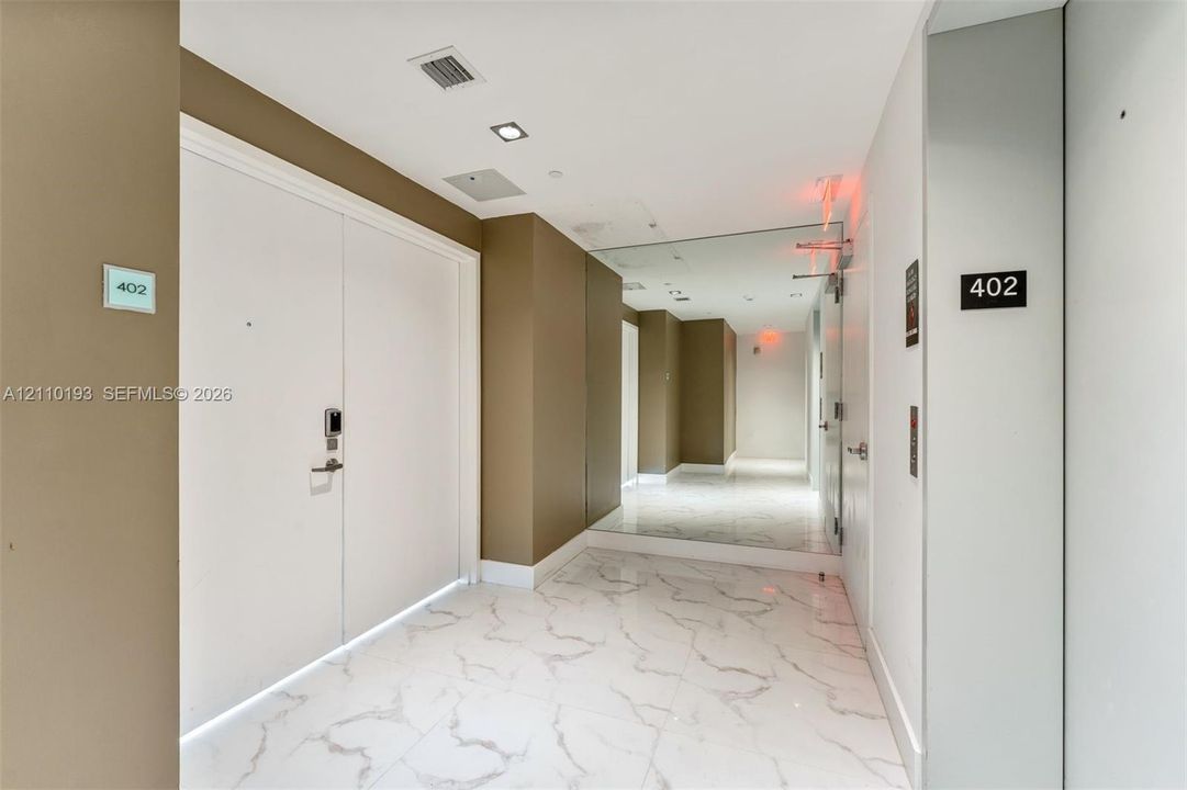 Entryway featuring polished stone-finish tile flooring, recessed ceiling lighting, and floor-to-ceiling mirror paneling