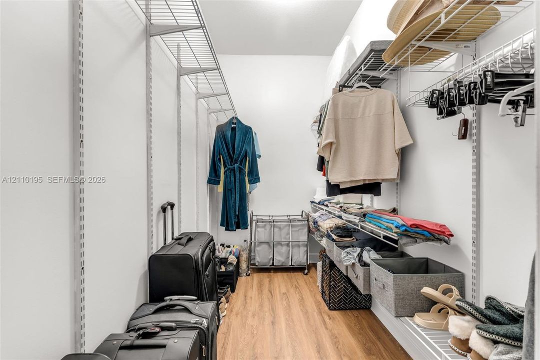 Walk-in storage space featuring wood-finish flooring and tiered wire shelving systems