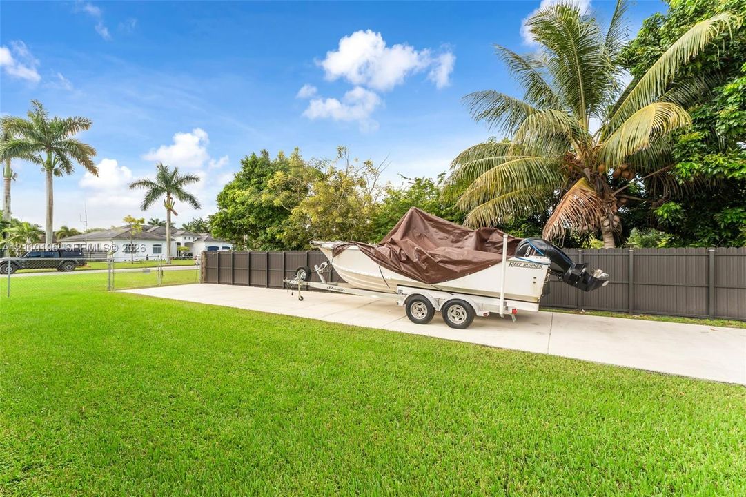 Expansive concrete pad, dark-finish privacy fencing, and manicured lawn