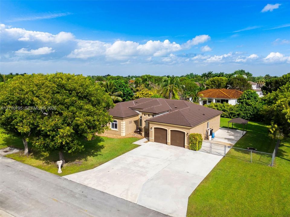 Single-story residence featuring a tile roof, two-car garage, concrete driveway, and fenced perimeter yard with mature landscaping