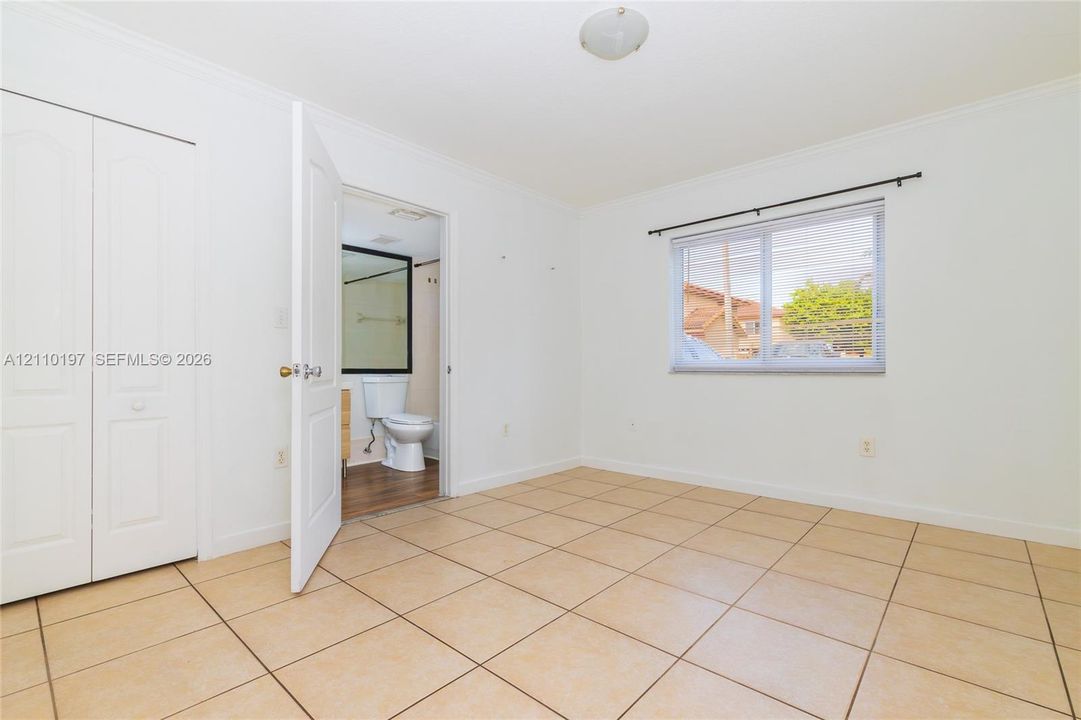 Neutral-toned tile flooring, white-finish bi-fold closet doors, and a horizontal sliding window