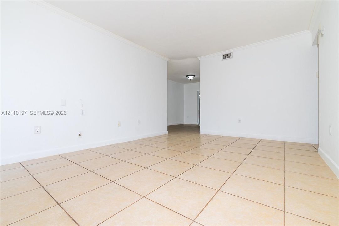 Neutral-toned ceramic tile flooring, crown molding, and smooth-finish walls