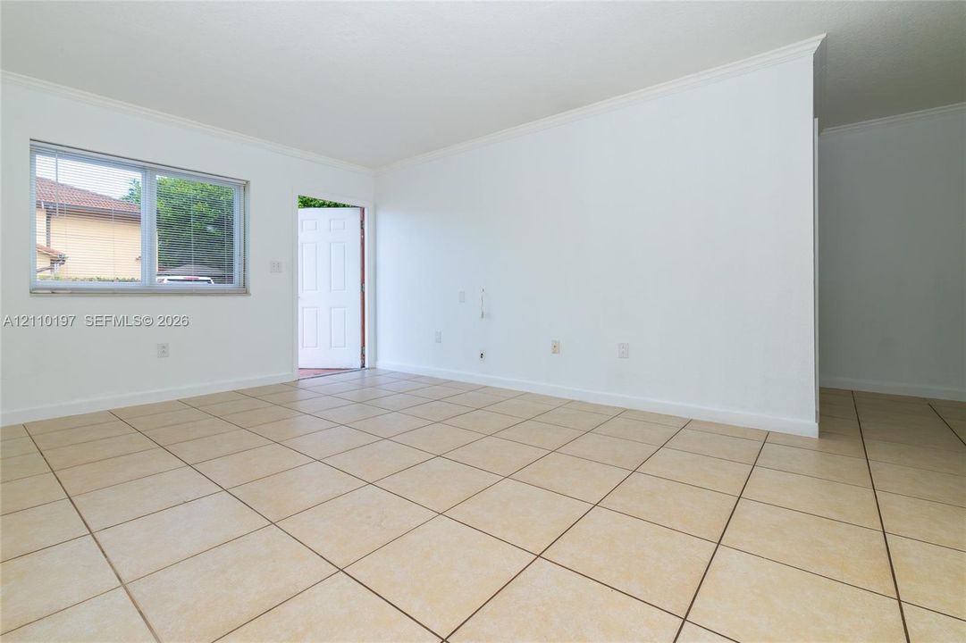 Neutral-toned tile flooring, white wall finishes, crown molding, and a single-pane horizontal window