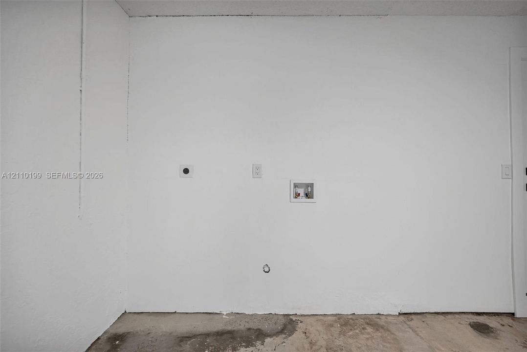 Dedicated utility area featuring washer and dryer hookups, recessed plumbing supply box, and electrical outlet