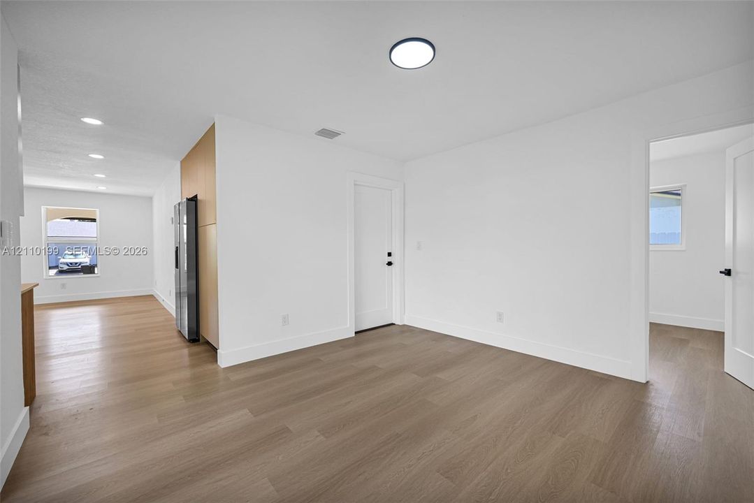 Interior space featuring light-toned wood-finish flooring, recessed LED lighting, flat-panel cabinetry, and white shaker-style doors