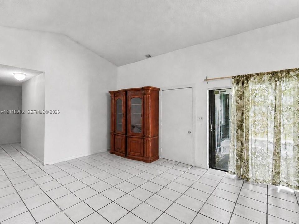 Vaulted ceiling, ceramic tile flooring, and glass sliding door providing exterior access