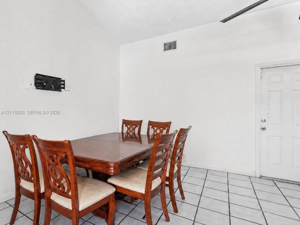 Neutral-toned interior space featuring light-colored tile flooring, high-reaching walls, and a white paneled entry door
