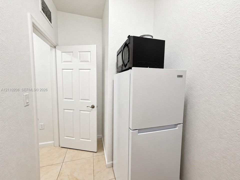 Interior area featuring neutral tile flooring, a white six-panel door with a metallic handle, and smooth-finish walls