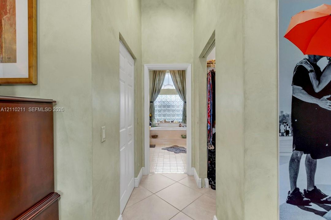 Bathroom featuring a recessed soaking tub with a tiled surround, glass block window, separate shower stall with a glass enclosure, and dual cabinetry with dark stone countertops