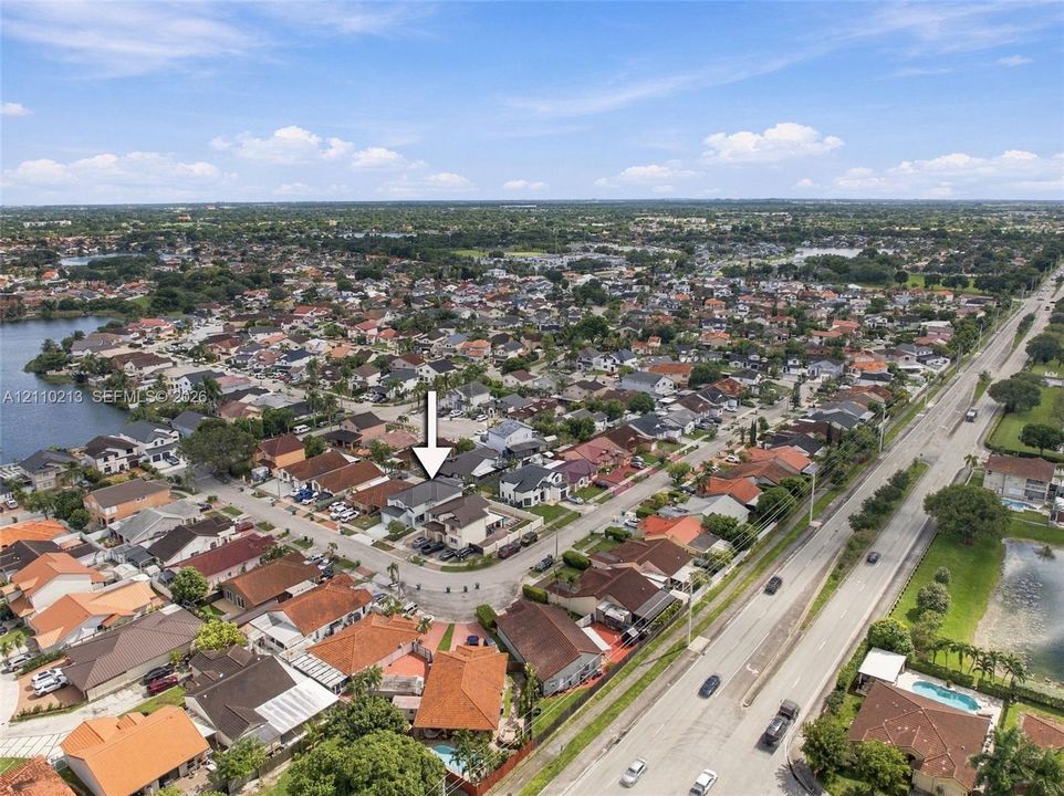 Aerial perspective of a single-family residence situated on a corner lot within a residential community, featuring a multi-pitched roofline and a concrete driveway