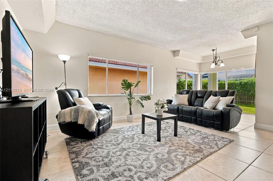 Living area featuring tile flooring, large windows, and a multi-arm ceiling light fixture