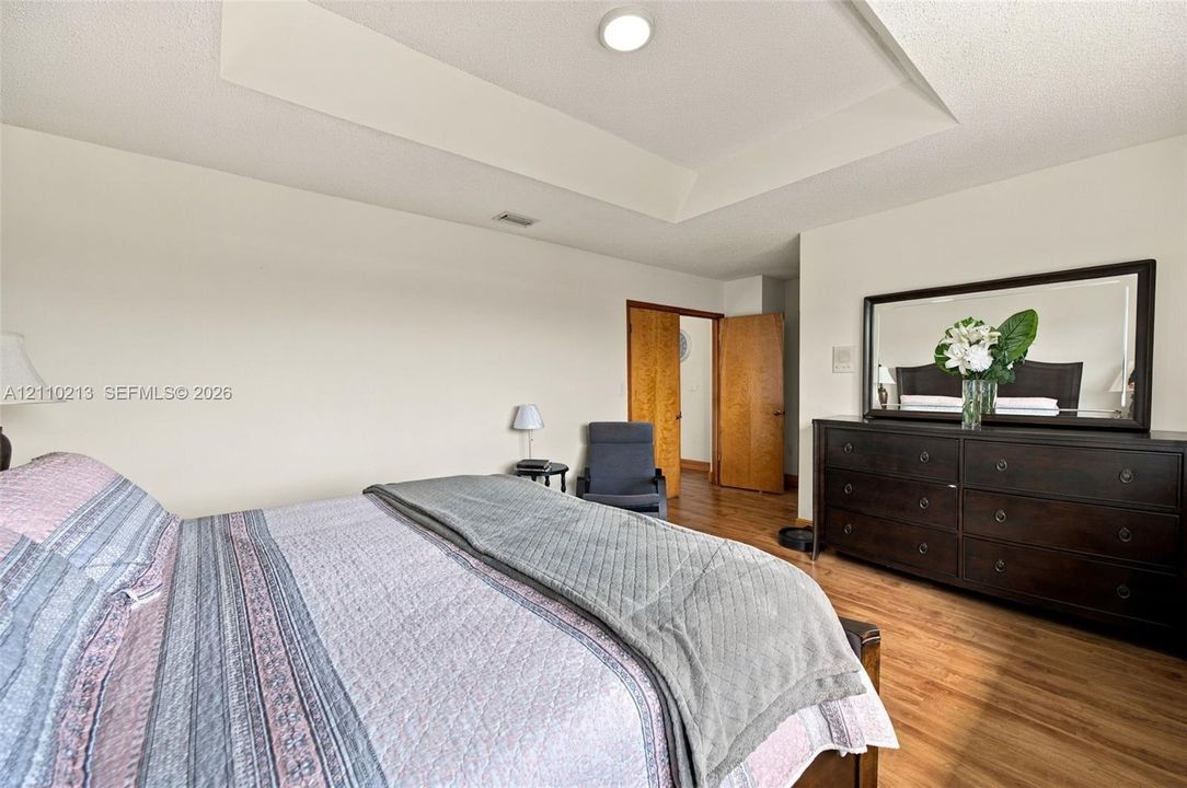 Room featuring a tray ceiling, recessed lighting, and wood-finish flooring with solid-core wood doors