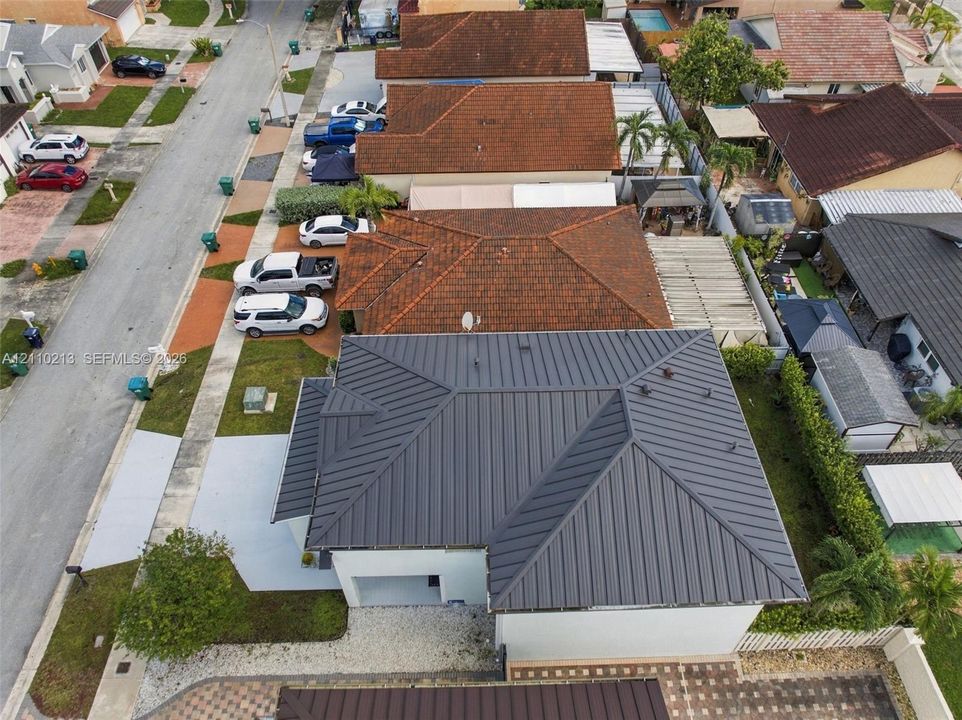 Standing seam metal roof, paved driveway, and side-entry garage