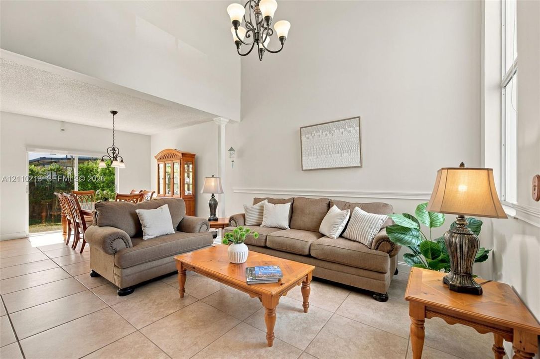 Vaulted ceilings, large-format tile flooring, decorative chair rail molding, and multiple multi-arm chandeliers