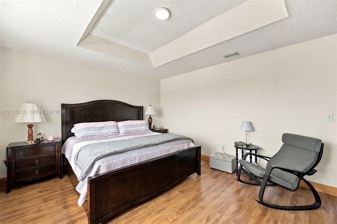 Room featuring a tray ceiling and wood-finish flooring