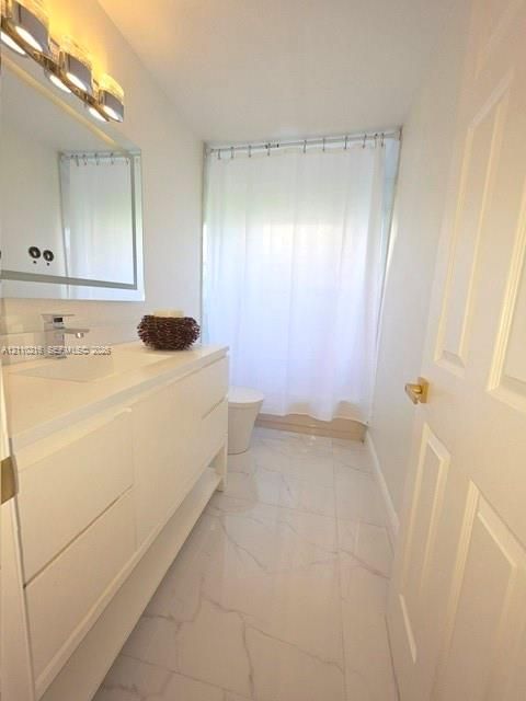 Bathroom featuring a modern white floating vanity with an integrated basin, polished metal faucet, multi-bulb vanity lighting, and light-toned tile flooring