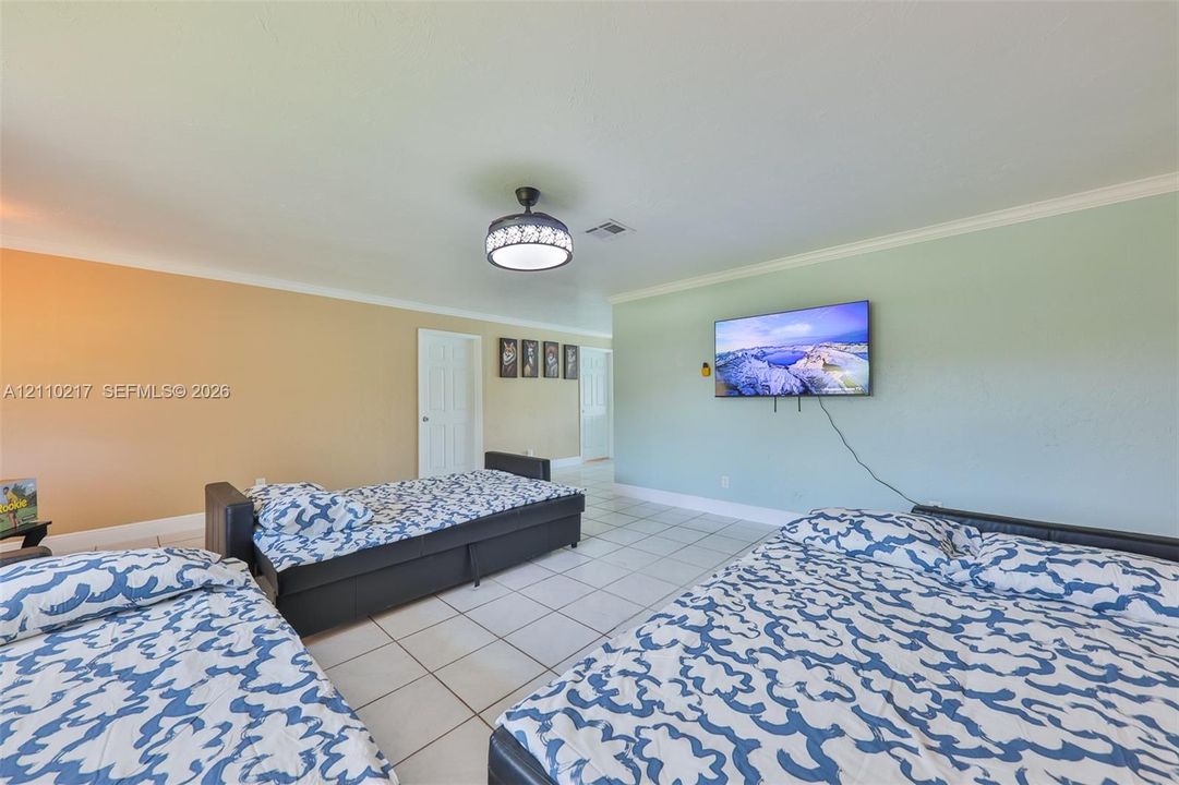 Spacious interior featuring neutral tile flooring, crown molding, and a contemporary drum-style ceiling light fixture