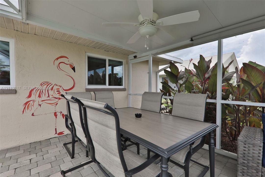 Screened-in patio featuring paver flooring, a white ceiling fan, and a covered roof structure