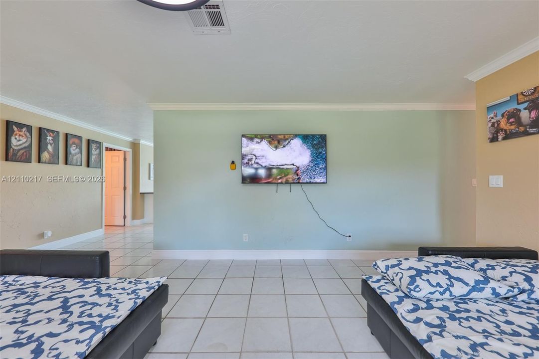 Interior space featuring white tiled flooring, crown molding, and an accent wall