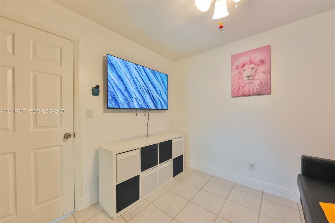 Ceramic tile flooring, white interior walls, solid-core interior door, and multi-arm ceiling fixture