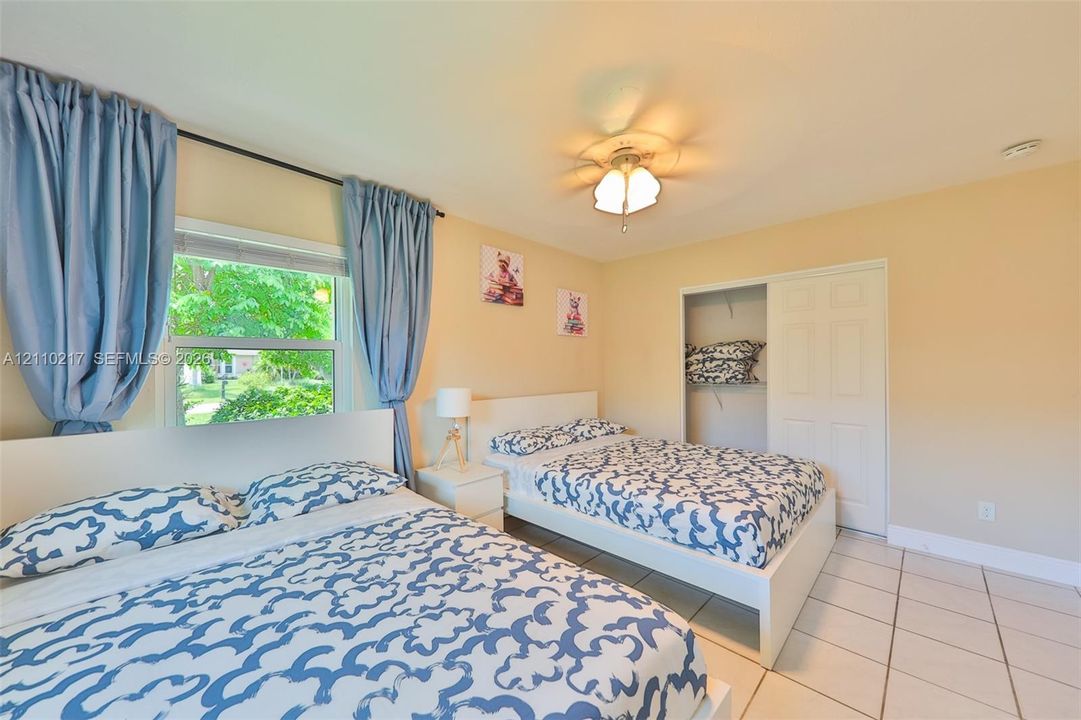 Room featuring tile flooring, a window providing natural light, a ceiling-mounted light fixture, and a built-in sliding-door closet