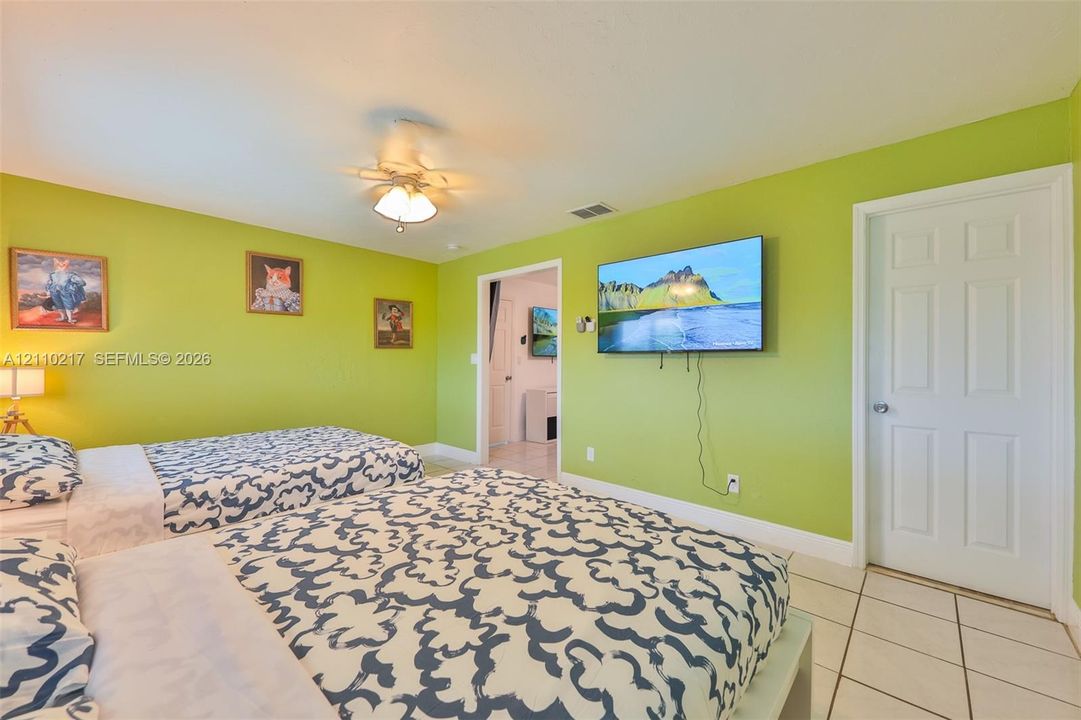 Room interior featuring ceramic tile flooring, a multi-blade ceiling fan with integrated lighting, and a six-panel interior door