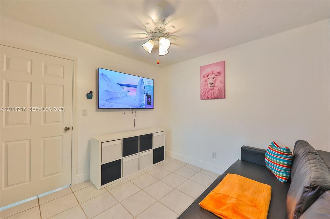 Ceramic tile flooring, white six-panel interior door, and ceiling-mounted light fixture with three glass shades