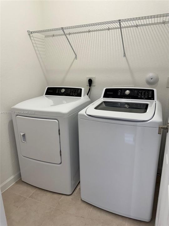 Utility space featuring tile flooring and integrated wire shelving