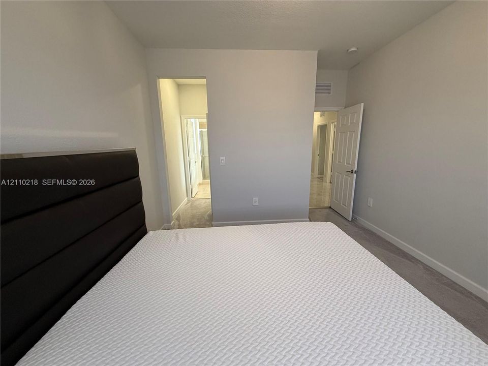Neutral-toned walls, high ceilings, and plush wall-to-wall carpeting, featuring a multi-panel interior door and architectural entryways