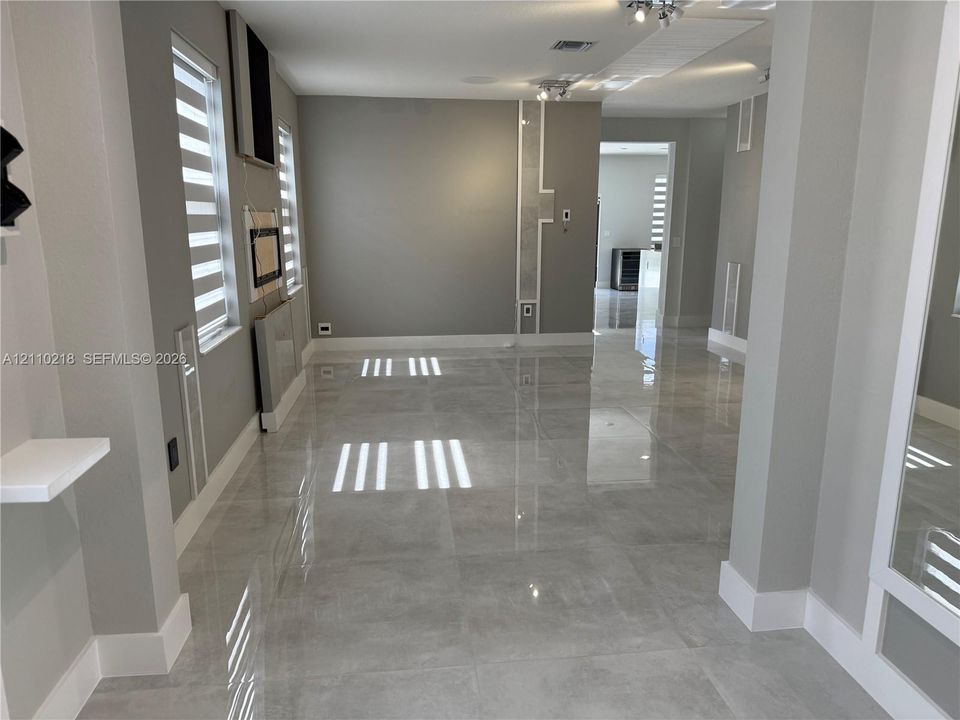 Large-format tile flooring, recessed ceiling lighting, custom wall molding details, and layered window treatments