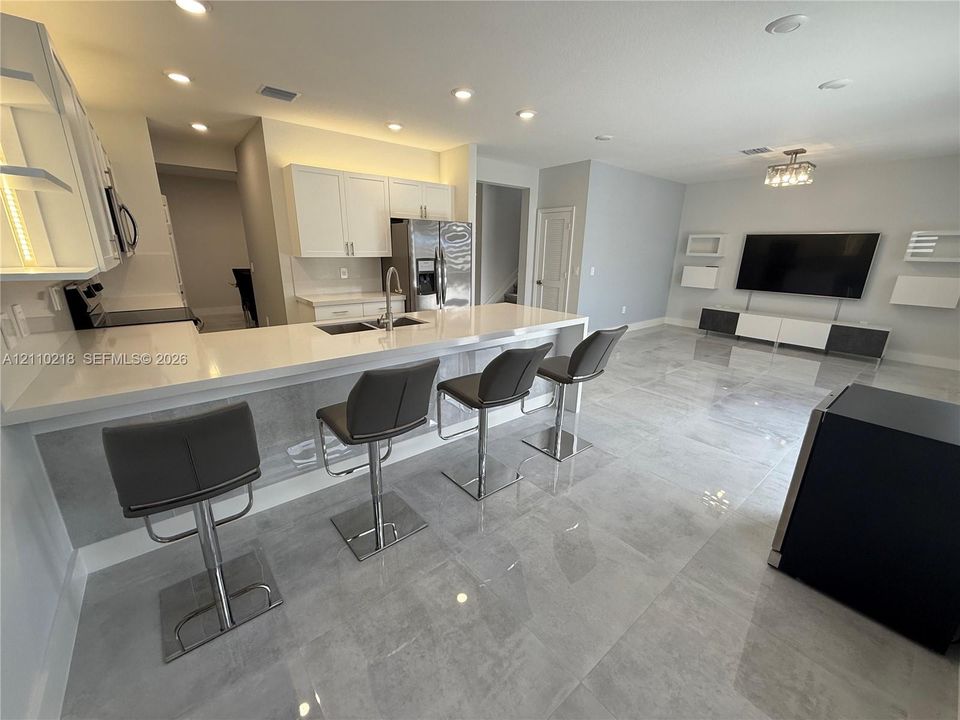 Kitchen featuring white cabinetry, solid-surface countertops, recessed lighting, and large-format tile flooring