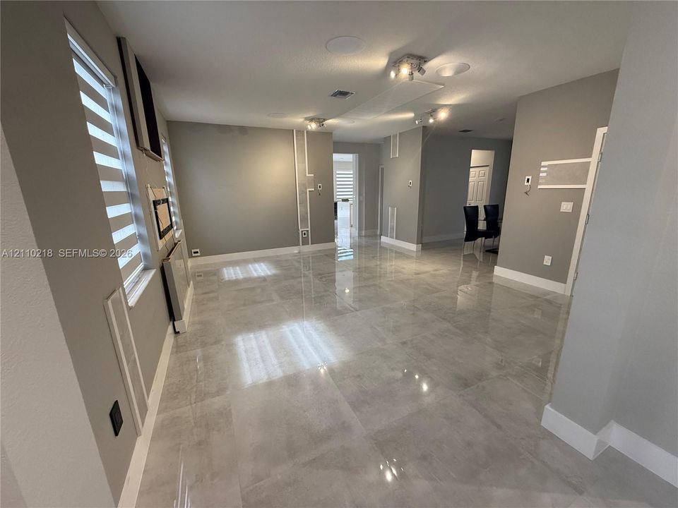 Large-format tile flooring, recessed ceiling lighting, and windows with layered roller shades