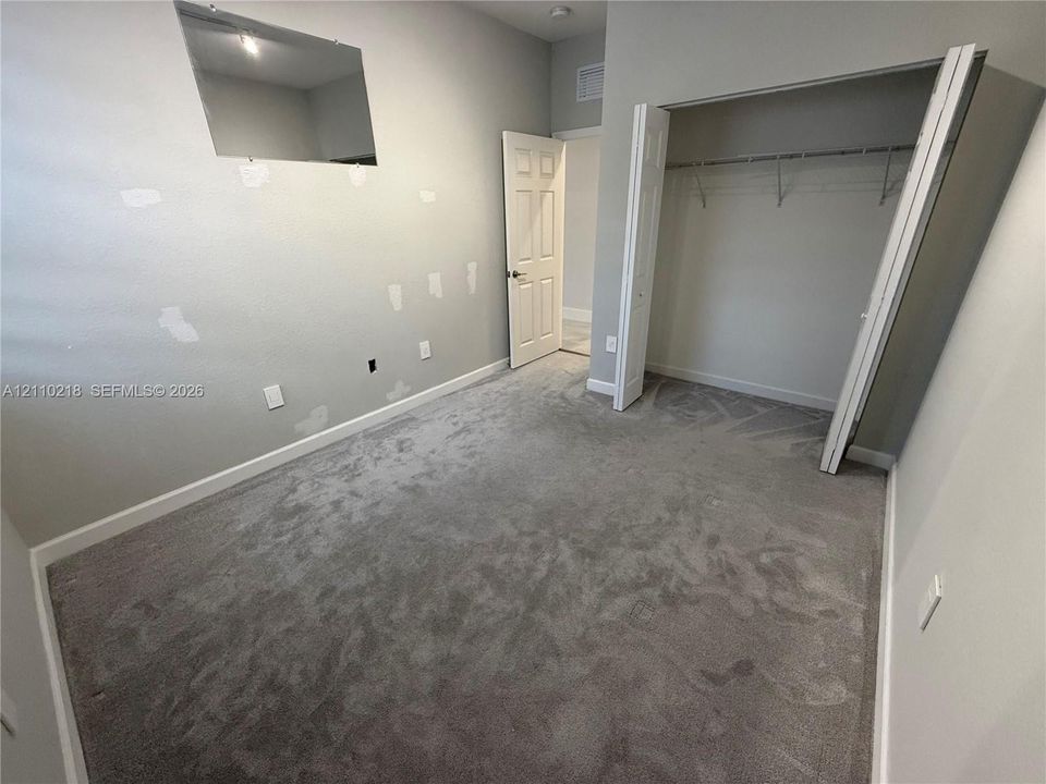 Neutral-toned interior space featuring plush wall-to-wall carpeting, a six-panel interior door, and a built-in closet with double bi-fold doors