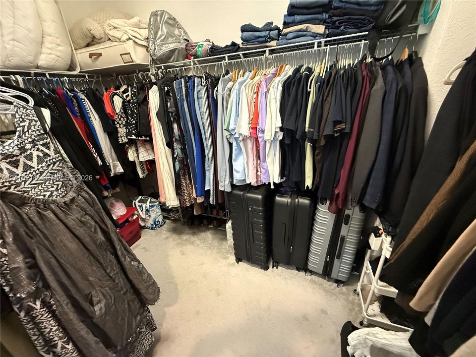Walk-in closet featuring tiered wire shelving and integrated hanging rods