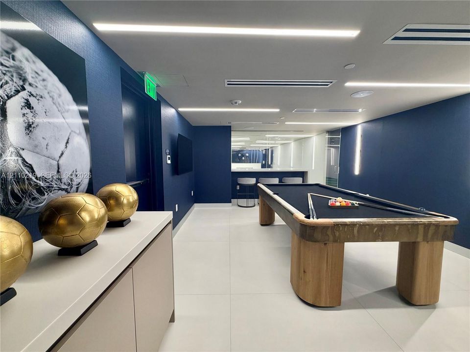 Recessed linear lighting, large-format tile flooring, built-in cabinetry with a smooth-surface countertop, and a built-in bar area