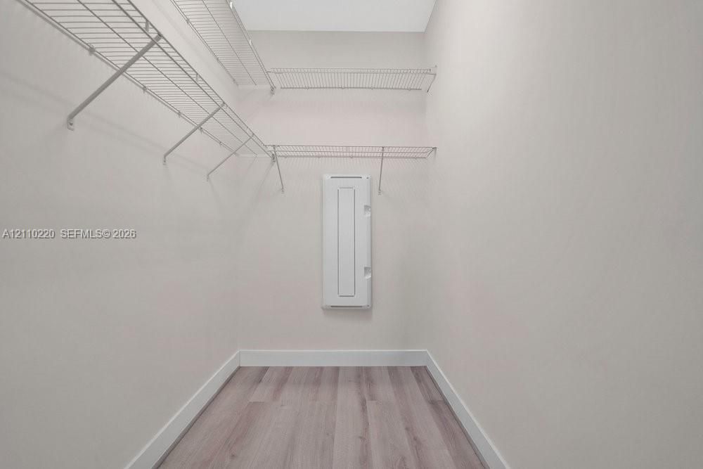 Storage space featuring tiered wire shelving and wood-finish flooring