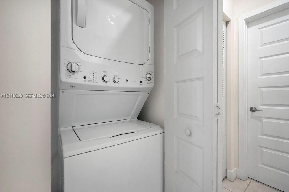 Stacked washer and dryer unit, louvered bi-fold closet doors, and solid-core paneled interior door