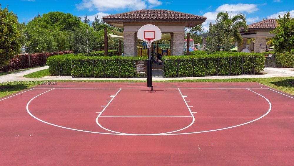 Outdoor basketball court featuring a paved surface, built-in hoop, and manicured landscaping