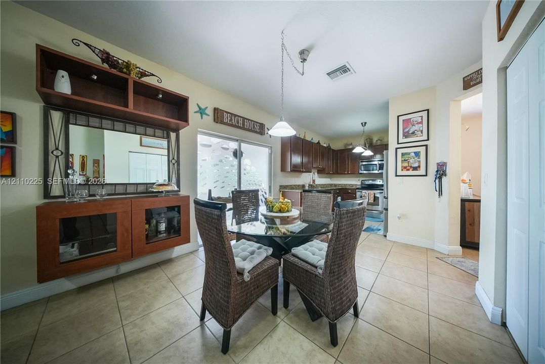 Kitchen area featuring wood cabinetry, stone countertops, stainless steel appliances, ceramic tile flooring, and built-in wall cabinetry with a mirror inlay