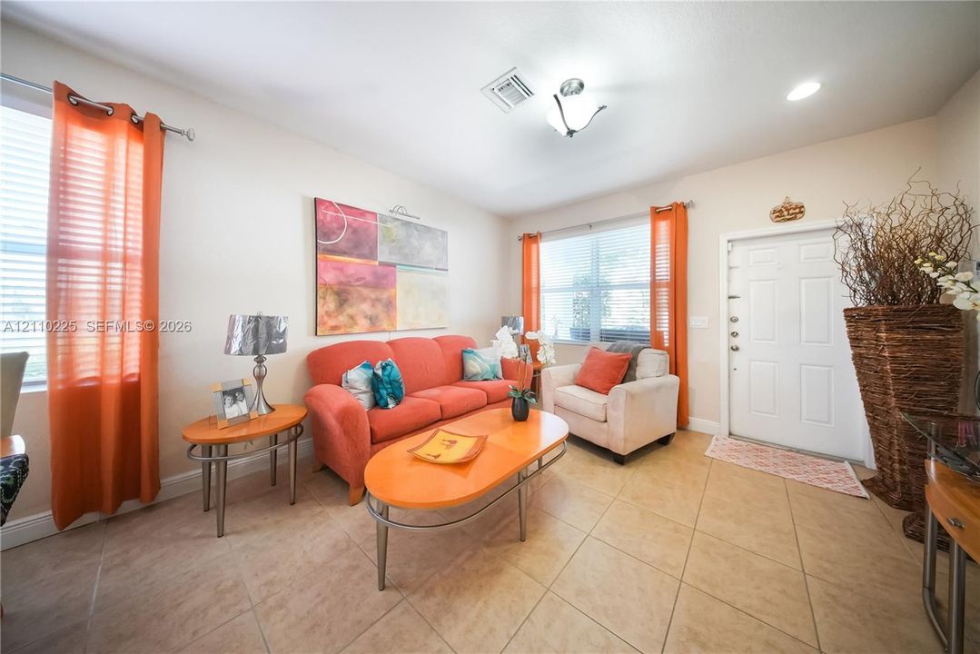 Living area featuring large-format ceramic tile flooring, dual-pane windows, and a flush-mount light fixture