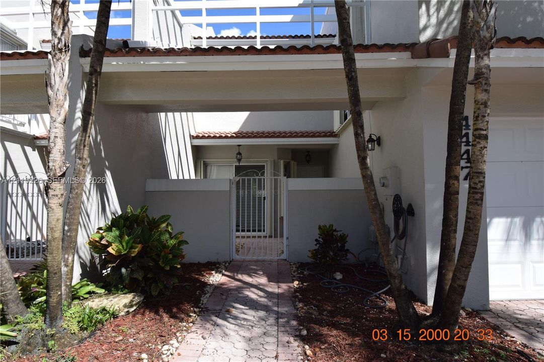 Exterior facade featuring a tile roof, covered entryway, private gated courtyard, and attached garage