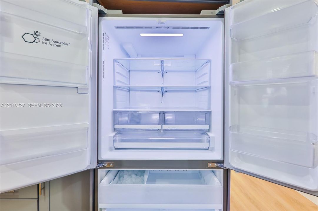 Stainless steel French door refrigerator featuring an integrated ice system, adjustable glass shelving, and humidity-controlled crisper drawers