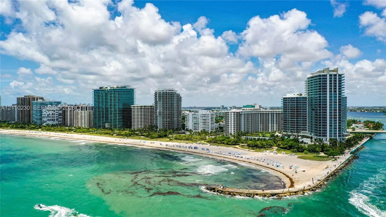 Coastal high-rise buildings situated along a sandy shoreline with a stone jetty and direct Atlantic Ocean frontage