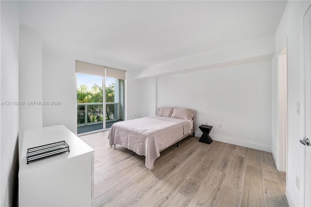 Interior space featuring wood-finish flooring, neutral wall tones, and a floor-to-ceiling glass sliding door providing outdoor access