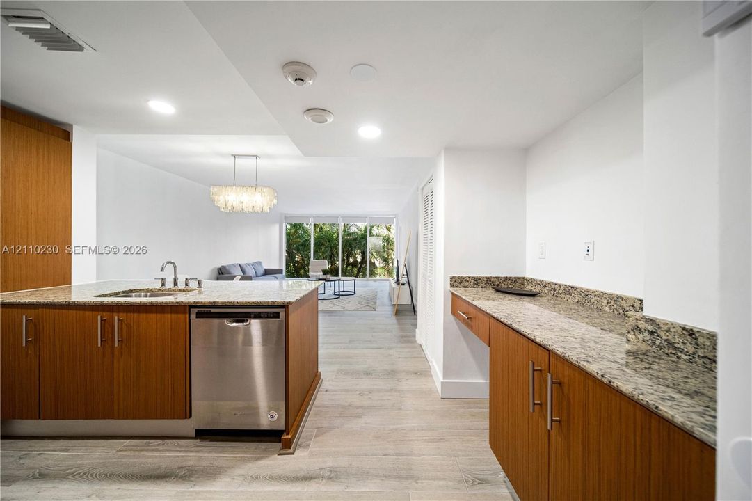Kitchen featuring wood-finish cabinetry, stone countertops, stainless steel dishwasher, recessed lighting, and wood-finish flooring