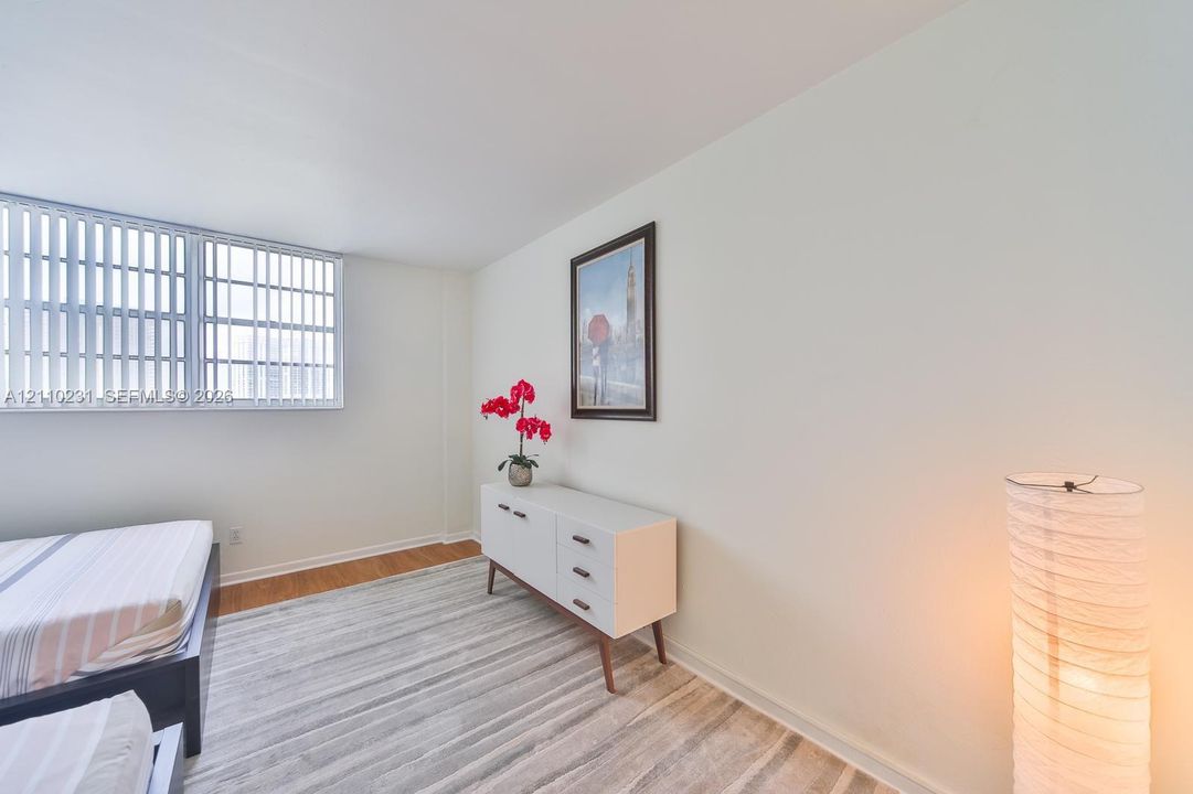 Neutral-toned room featuring expansive horizontal windows with vertical blinds and wood-finish flooring