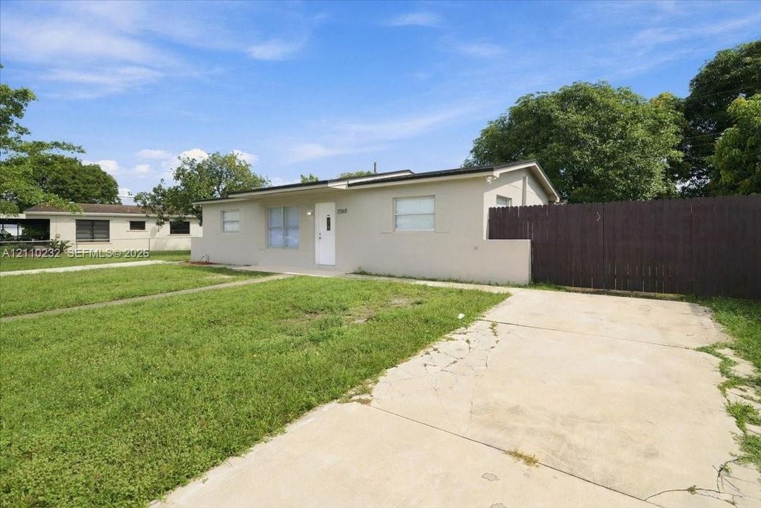 Single-story exterior featuring a smooth stucco finish, concrete driveway, and solid wood fencing