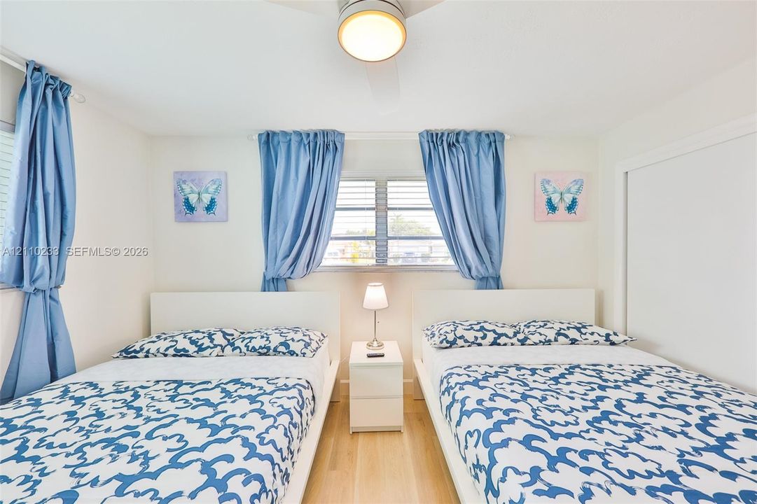 Bedroom featuring wood-finish flooring, louvered windows, and a ceiling-mounted light fixture