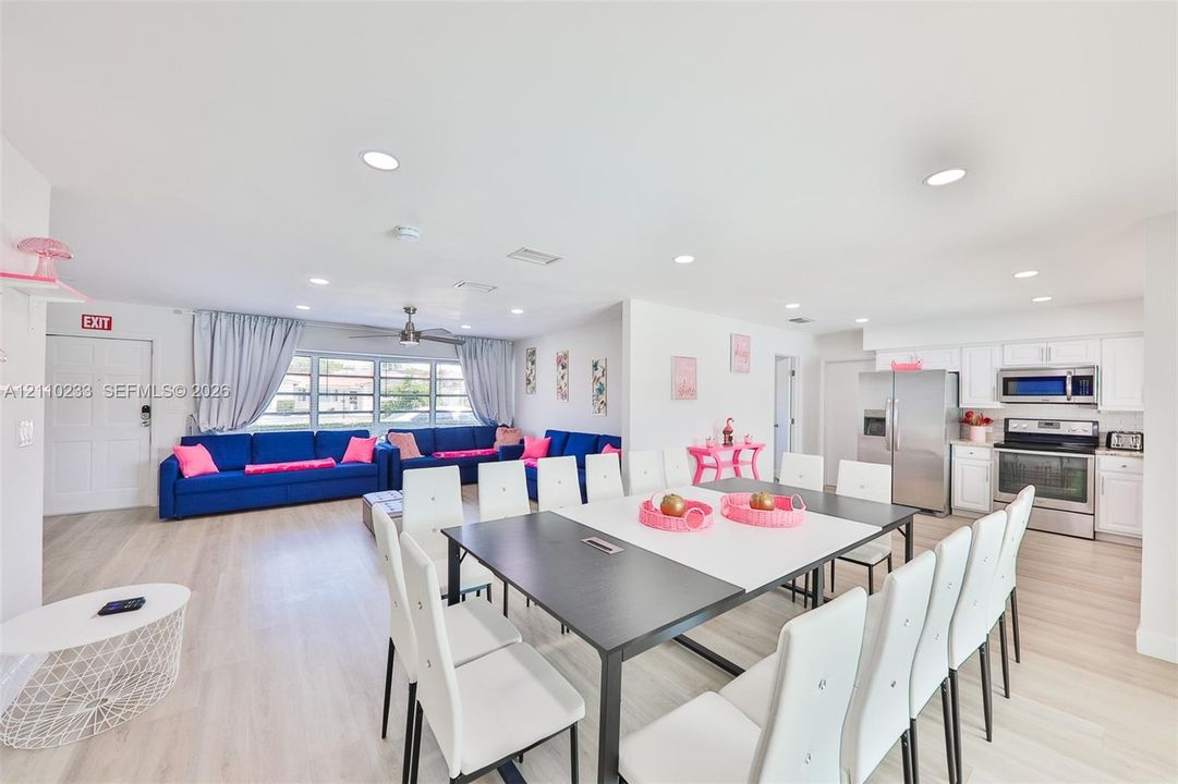 Open-concept living space featuring wood-finish flooring, recessed lighting, white cabinetry, stainless steel appliances, and a central ceiling fan