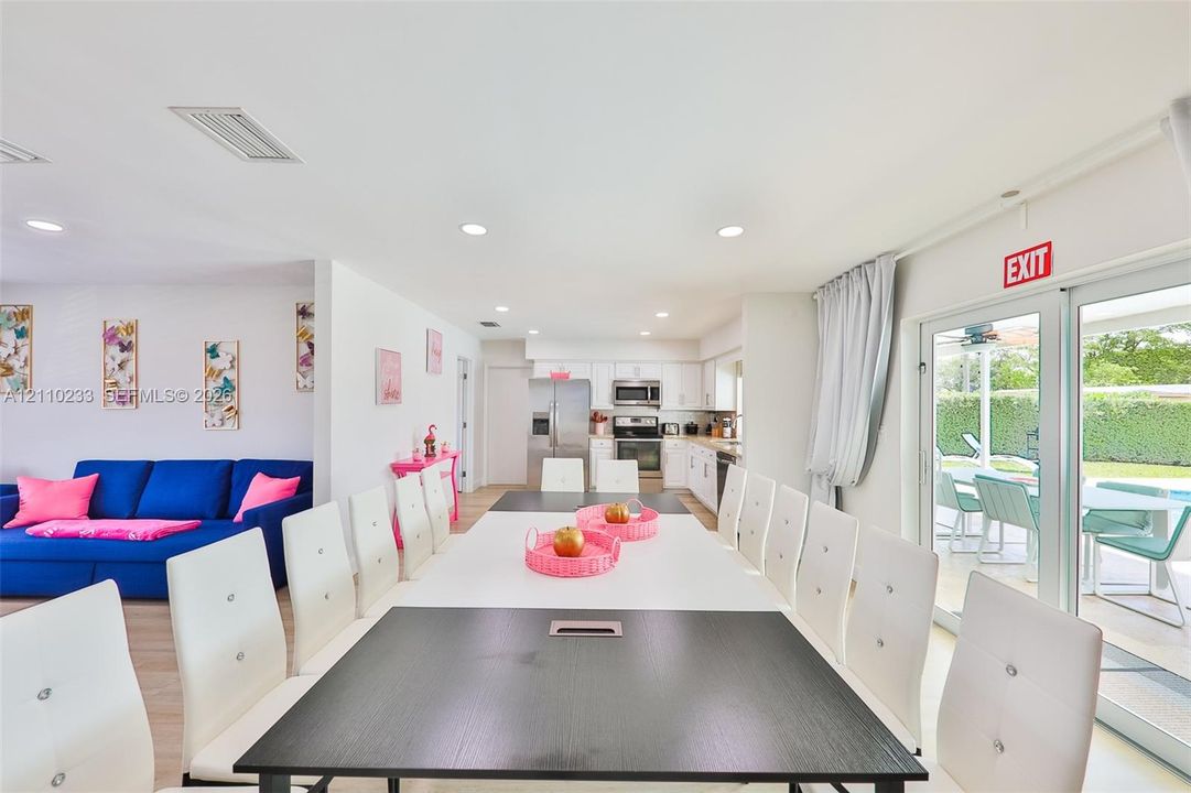 Open-concept interior featuring recessed lighting, light-toned flooring, and white kitchen cabinetry with stainless steel appliances